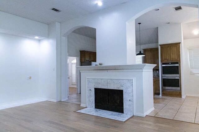 2104 Hunter Place Ln, Arlington, TX 76006 - unfurnished living room with arched walkways, light wood-style flooring, a high end fireplace, recessed lighting, and baseboards