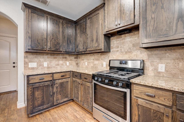 320 Collins St, Argyle, TX 76226 - kitchen with gas range, arched walkways, backsplash, and light stone countertops