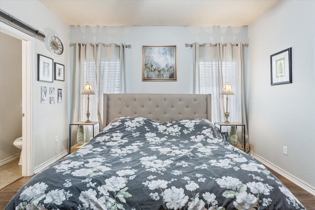 10285 Peony Ln, Waco, TX 76708 - bedroom featuring wood finished floors, a barn door, ensuite bathroom, and baseboards