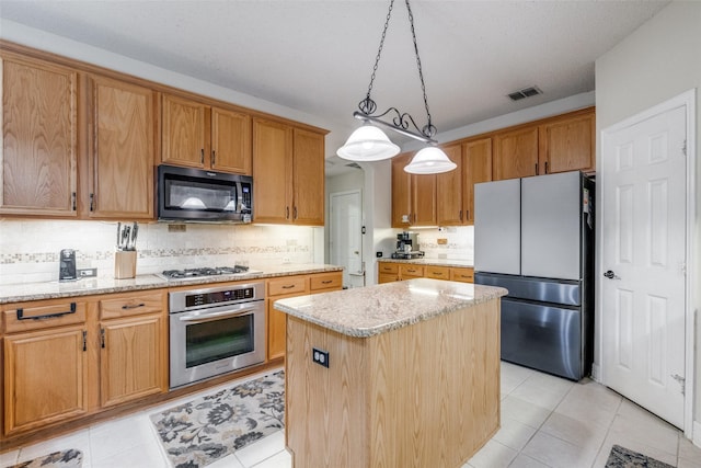 1109 Huntington Trl, Mansfield, TX 76063 - kitchen with stainless steel appliances, a center island, light tile patterned flooring, decorative backsplash, and light stone counters