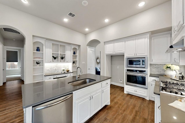 12164 Curry Creek Dr, Frisco, TX 75035 - kitchen featuring appliances with stainless steel finishes, a sink, arched walkways, decorative backsplash, and white cabinets