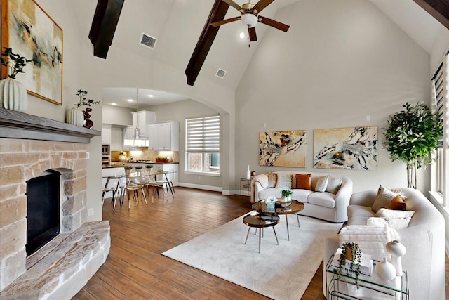 12164 Curry Creek Dr, Frisco, TX 75035 - living area with high vaulted ceiling, a ceiling fan, arched walkways, beamed ceiling, and a stone fireplace