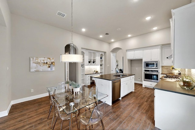 12164 Curry Creek Dr, Frisco, TX 75035 - kitchen with stainless steel appliances, dark countertops, a sink, dark wood-type flooring, and recessed lighting