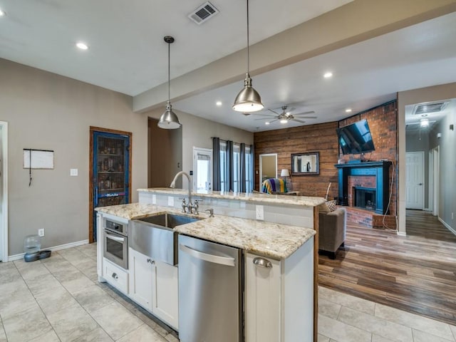605 Lakeridge Dr, Lavon, TX 75166 - kitchen featuring appliances with stainless steel finishes, a sink, an island with sink, ceiling fan, and wooden walls