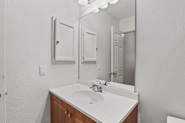 2323 Weatherby Dr, Mesquite, TX 75181 - half bathroom featuring vanity, a textured wall, and toilet