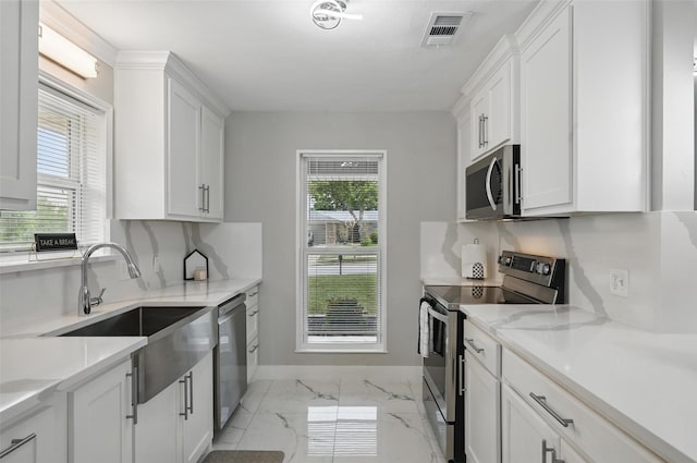 1632 Pecan Park Dr, Arlington, TX 76012 - kitchen with stainless steel appliances, light marble finish floors, a sink, baseboards, and white cabinetry