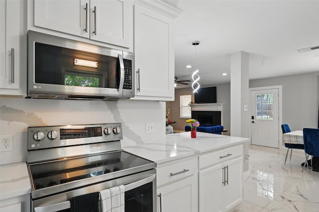 1632 Pecan Park Dr, Arlington, TX 76012 - kitchen with appliances with stainless steel finishes, light marble finish flooring, a fireplace, white cabinetry, and recessed lighting