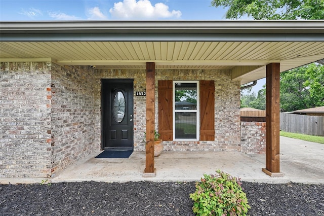 1632 Pecan Park Dr, Arlington, TX 76012 - doorway to property featuring fence, covered porch, and brick siding