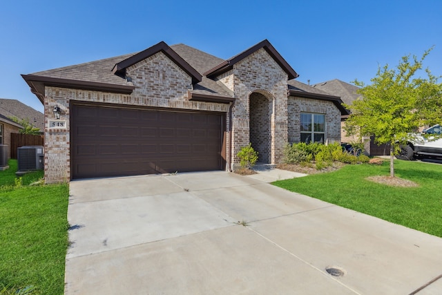 548 Bradley Dr, Fate, TX 75087 - french country inspired facade with cooling unit, brick siding, a front lawn, a garage, and concrete driveway