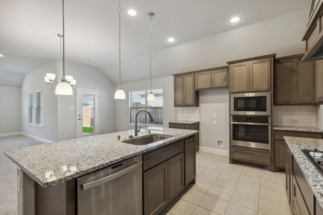 548 Bradley Dr, Fate, TX 75087 - kitchen with stainless steel appliances, a sink, baseboards, a kitchen island with sink, and light stone counters