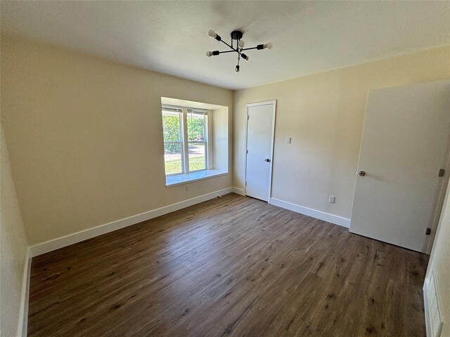 1153 Tracy Ln, Lancaster, TX 75134 - unfurnished bedroom featuring dark wood-type flooring, baseboards, and a chandelier
