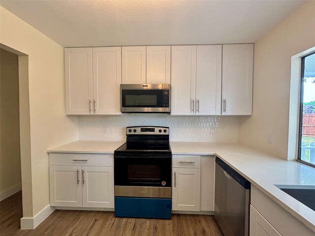 1153 Tracy Ln, Lancaster, TX 75134 - kitchen featuring stainless steel appliances, light wood-style floors, white cabinets, and tasteful backsplash