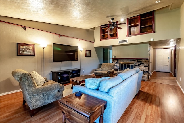 2606 Cedar Elm Ln, Garland, TX 75043 - living room with a glass covered fireplace, wood finished floors, a ceiling fan, baseboards, and a textured ceiling