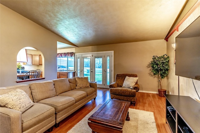 2606 Cedar Elm Ln, Garland, TX 75043 - living area with wood finished floors, vaulted ceiling, arched walkways, and baseboards