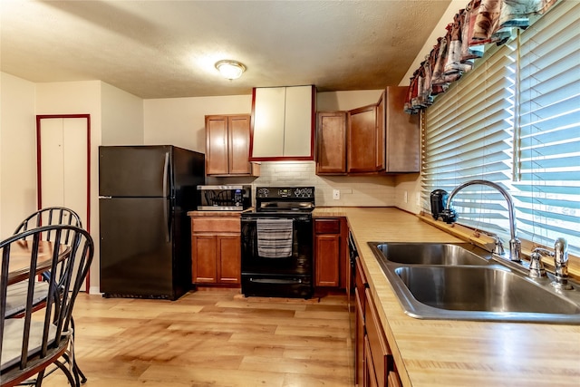 2606 Cedar Elm Ln, Garland, TX 75043 - kitchen with black appliances, a sink, light wood finished floors, backsplash, and brown cabinetry
