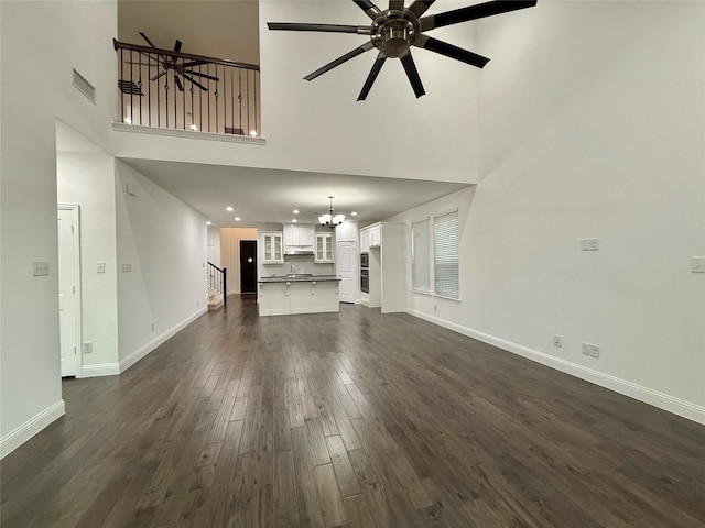 1103 Bantham Way, Forney, TX 75126 - unfurnished living room featuring a chandelier, a towering ceiling, baseboards, dark wood finished floors, and a ceiling fan