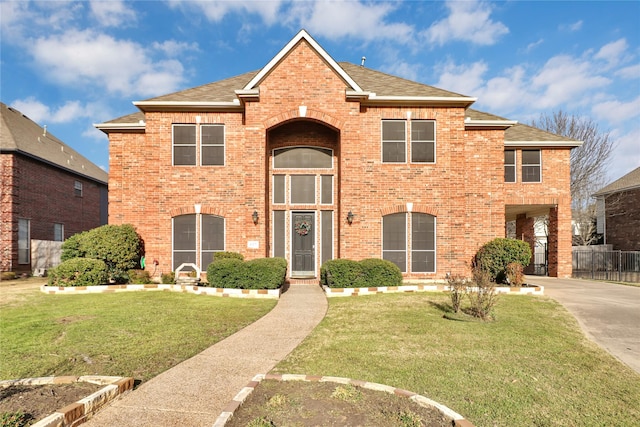 traditional home with brick siding, a front yard, roof with shingles, driveway, and a carport
