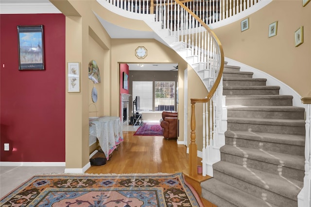 foyer featuring stairway, baseboards, wood finished floors, and a high ceiling