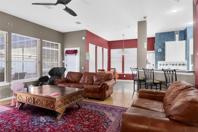 living area featuring ceiling fan, light wood-style flooring, a chandelier, and baseboards