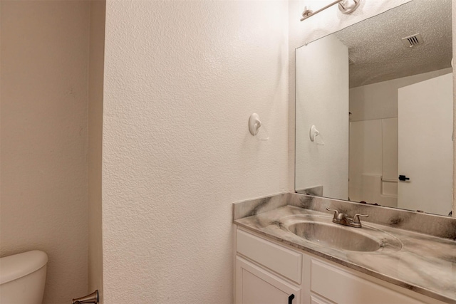 914 Gillon Dr, Arlington, TX 76001 - bathroom featuring a textured wall, toilet, vanity, and a textured ceiling