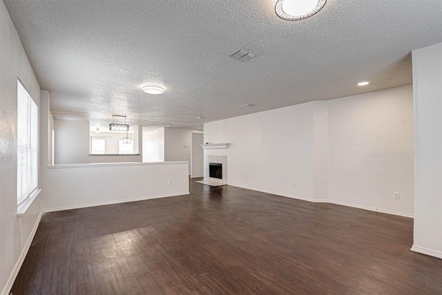 914 Gillon Dr, Arlington, TX 76001 - unfurnished living room with dark wood-type flooring, a textured ceiling, a tile fireplace, and baseboards