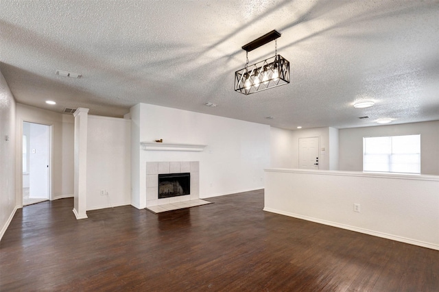 914 Gillon Dr, Arlington, TX 76001 - unfurnished living room with a textured ceiling, dark wood-style floors, baseboards, and a tiled fireplace