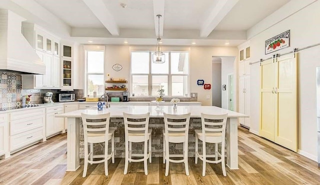 1926 N Stodghill Rd, Rockwall, TX 75087 - kitchen featuring custom exhaust hood, beamed ceiling, a kitchen island with sink, light countertops, and black electric stovetop