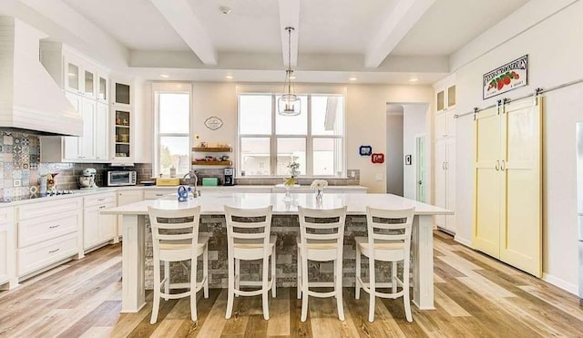 1926 N Stodghill Rd, Rockwall, TX 75087 - kitchen with custom exhaust hood, beamed ceiling, a kitchen island with sink, light countertops, and black electric cooktop