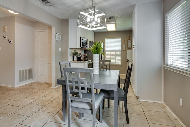6713 Windwillow Dr, Fort Worth, TX 76137 - dining space featuring light tile patterned flooring, a textured ceiling, a chandelier, and baseboards