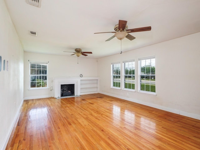 1803 4th St, Brownwood, TX 76801 - unfurnished living room featuring ceiling fan, light wood-type flooring, baseboards, and a fireplace with flush hearth