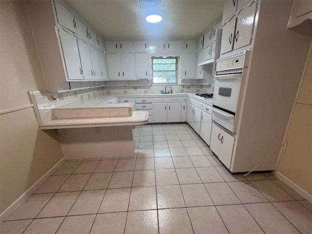 5708 Melinda St, Haltom City, TX 76117 - kitchen with oven, a warming drawer, tile counters, a sink, and a peninsula