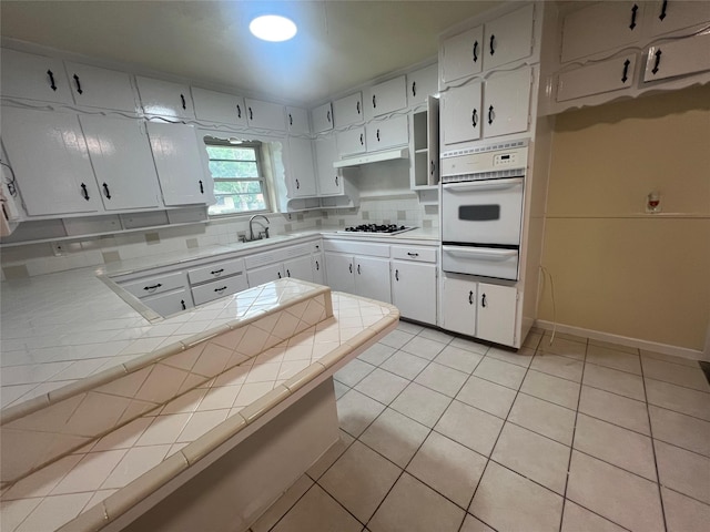 5708 Melinda St, Haltom City, TX 76117 - kitchen featuring a warming drawer, white appliances, tile counters, tasteful backsplash, and light tile patterned floors