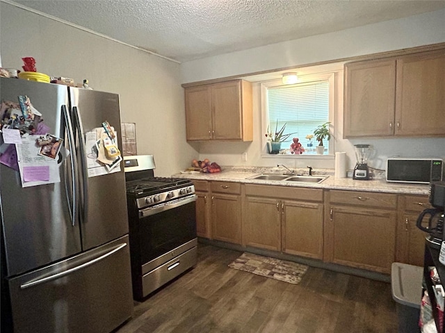 209 Kelly St, Bonham, TX 75418 - kitchen with stainless steel appliances, a sink, dark wood finished floors, a textured ceiling, and light countertops