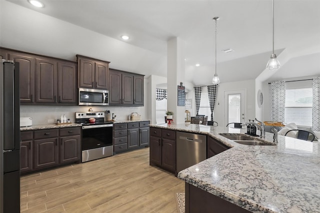 725 Sandy Chip Trl, Fort Worth, TX 76108 - kitchen with stainless steel appliances, a sink, dark brown cabinetry, decorative light fixtures, and light stone counters