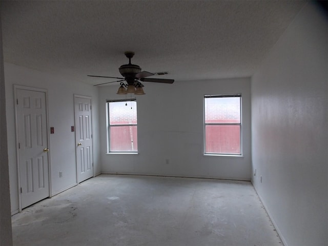 6107 Brookfall Dr, Arlington, TX 76018 - empty room with unfinished concrete floors, a ceiling fan, a textured ceiling, and baseboards