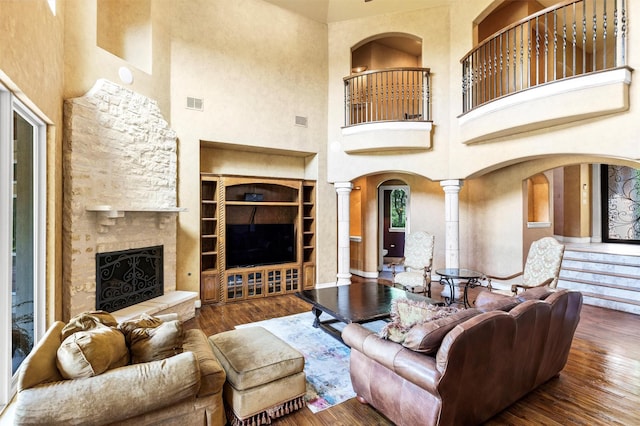 620 Timber Creek Cir, Stephenville, TX 76401 - living area with a high ceiling, a stone fireplace, hardwood / wood-style floors, ornate columns, and arched walkways