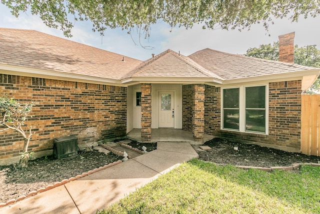 4107 Crossgate Ct, Arlington, TX 76016 - view of exterior entry with a chimney, brick siding, and a shingled roof
