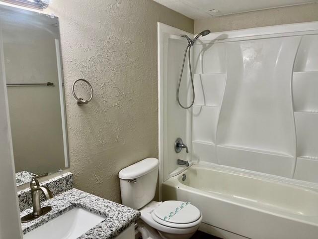 5636 Cherilee Ln, Haltom City, TX 76148 - full bathroom with a textured wall, toilet, shower / bath combination, and vanity