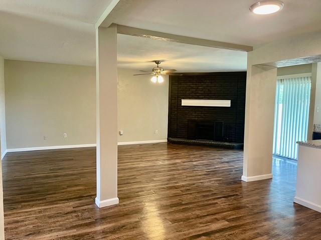 5636 Cherilee Ln, Haltom City, TX 76148 - unfurnished living room with ceiling fan, dark wood-style flooring, baseboards, and a fireplace
