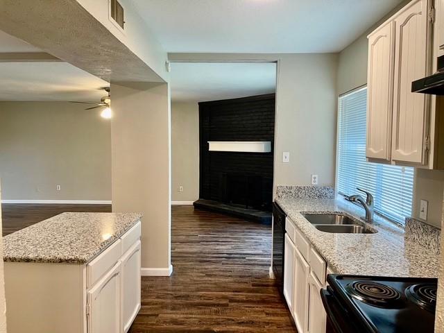 5636 Cherilee Ln, Haltom City, TX 76148 - kitchen with black appliances, ceiling fan, baseboards, and light stone countertops