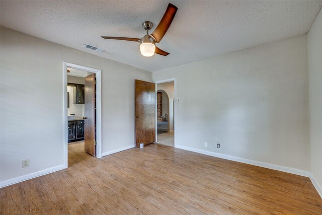 146 Circle Dr, Denison, TX 75021 - unfurnished bedroom featuring arched walkways, wood finished floors, baseboards, a textured ceiling, and ensuite bathroom