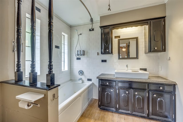 146 Circle Dr, Denison, TX 75021 - bathroom featuring crown molding, vanity, wood finished floors, a combined bath / shower with jetted tub, and tasteful backsplash