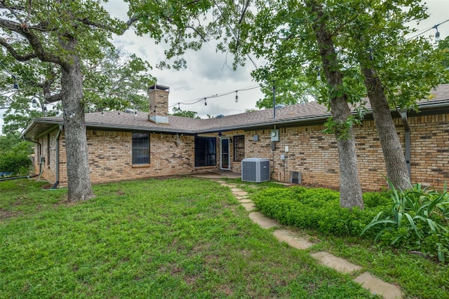 146 Circle Dr, Denison, TX 75021 - back of house with central AC, brick siding, a chimney, and a lawn