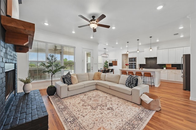 917 County Road 914, Burleson, TX 76028 - living room featuring a fireplace with raised hearth, light wood-style floors, crown molding, a ceiling fan, and recessed lighting