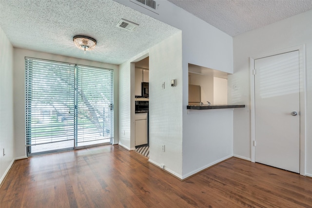 4211 Holland Ave Unit 206, Dallas, TX 75219 - spare room with a textured ceiling, wood finished floors, and baseboards