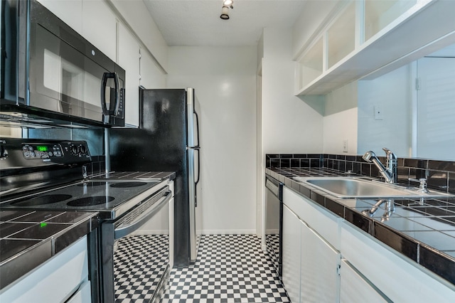 4211 Holland Ave Unit 206, Dallas, TX 75219 - kitchen with black appliances, a sink, tile counters, white cabinets, and light flooring