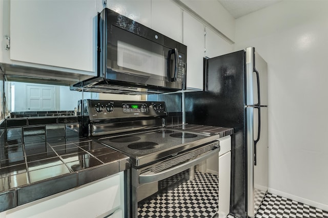 4211 Holland Ave Unit 206, Dallas, TX 75219 - kitchen featuring electric range oven, black microwave, tile patterned floors, white cabinetry, and tile countertops