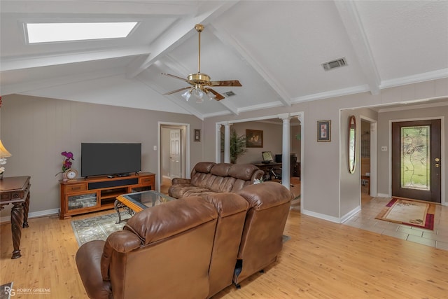 living area featuring decorative columns, light wood-style flooring, a ceiling fan, a skylight, and baseboards
