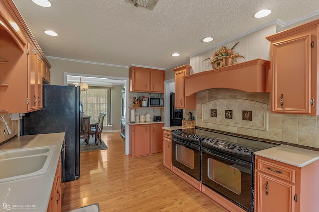 kitchen featuring black appliances, a sink, crown molding, light wood-style flooring, and backsplash