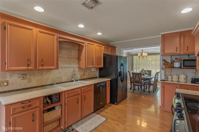kitchen with black appliances, a sink, light wood-type flooring, a chandelier, and backsplash